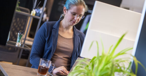 Medewerker van I-Experts werkt geconcentreerd op een laptop in een moderne kantooromgeving, wat de flexibiliteit van remote desktop mogelijkheden illustreert.